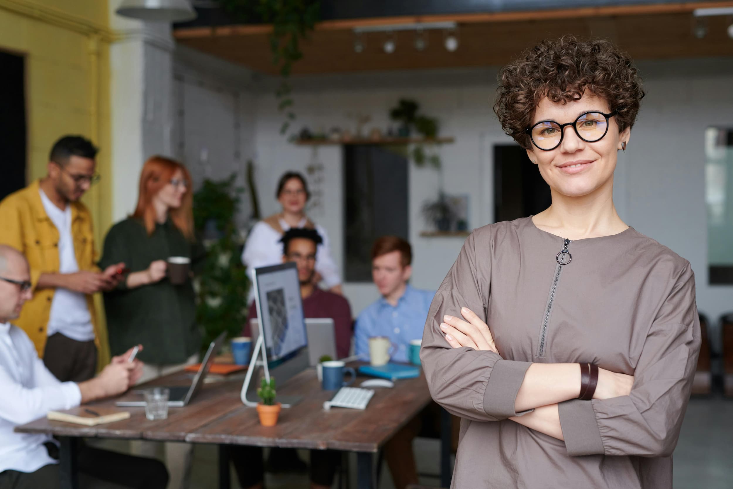 Woman with crossed arms smiling with team behind her