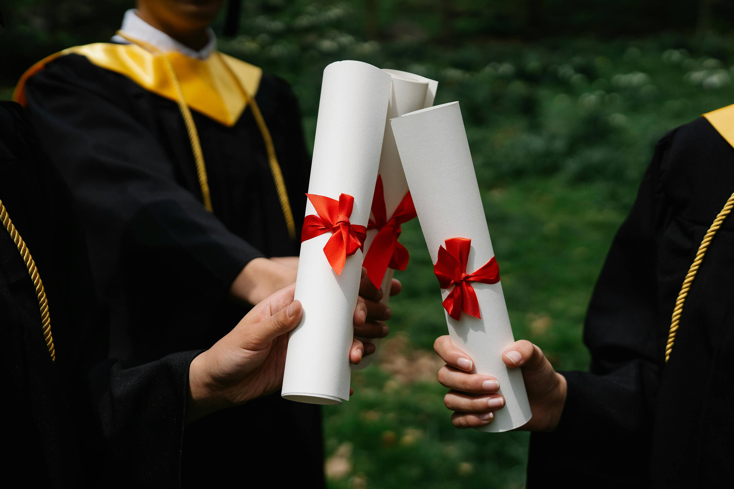 Three graduates showing their degree scrolls