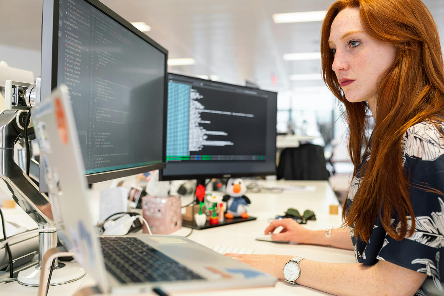 Woman working at a laptop with two additional screens